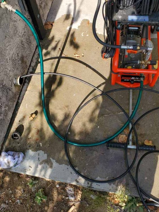 A professional drain cleaning machine with attached hoses and nozzles, ready for operation next to a residential building.