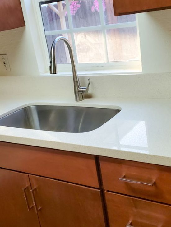 Updated kitchen with modern appliances and a stainless steel sink, highlighting clean countertops and a minimalist design.