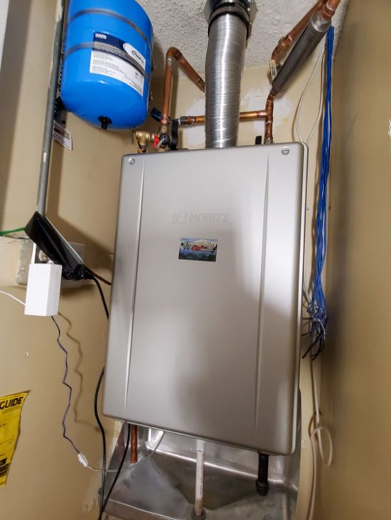 Noritz tankless water heater setup with expansion tank and ventilation in a small utility closet, enhancing space efficiency.