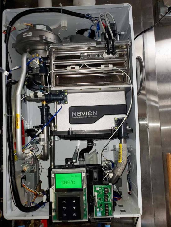Open internal view of a Navien condensing boiler showing detailed piping and digital temperature controls.