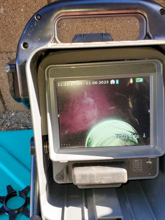 A digital monitor displaying the interior view of a sewer line during an inspection.