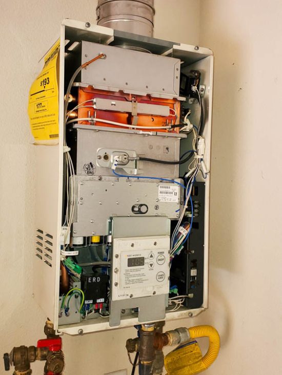 Open tankless water heater displaying its internal components and wiring, emphasizing detailed maintenance.