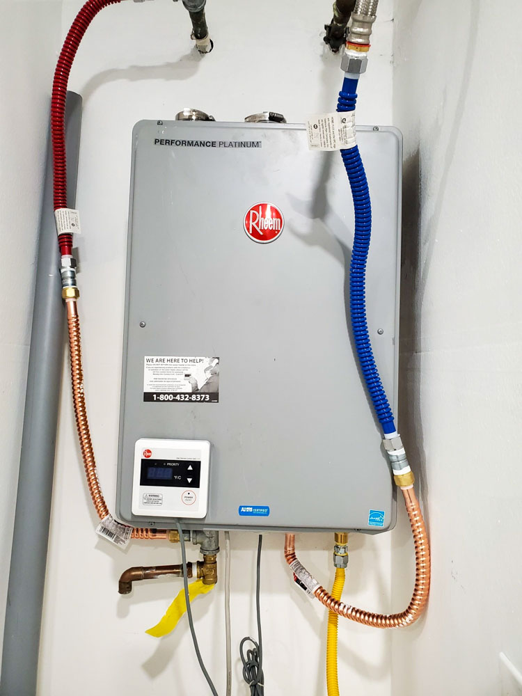 A wall-mounted Rheem Performance Platinum electric water heater with connected red and blue water lines.