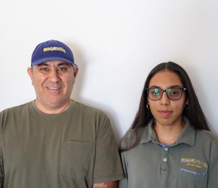 A portrait of a father and daughter plumbing team, standing confidently, highlighting their partnership and commitment to quality service.